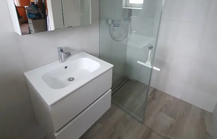 Detailaufnahme eines Neubau-Badezimmers mit individuellen Einbauschränken, großformatigen Fliesen und Design-Armaturen durch DMK Bau Reichelsheim.