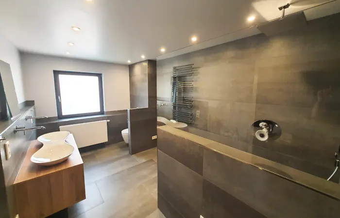 Moderne Badsanierung von DMK Bau Reichelsheim - komplett renoviertes Badezimmer mit bodengleicher Dusche und modernen Fliesen.
