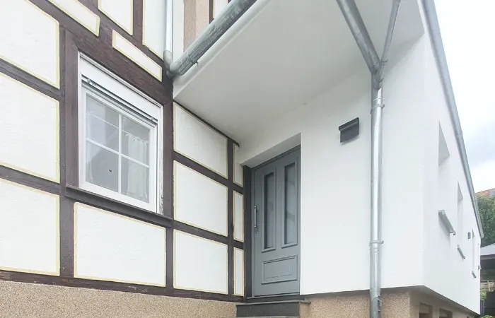 Detailaufnahme einer fachgerecht sanierten Fassade mit Wärmedämmverbundsystem und strukturiertem Außenputz durch DMK Bau Reichelsheim.